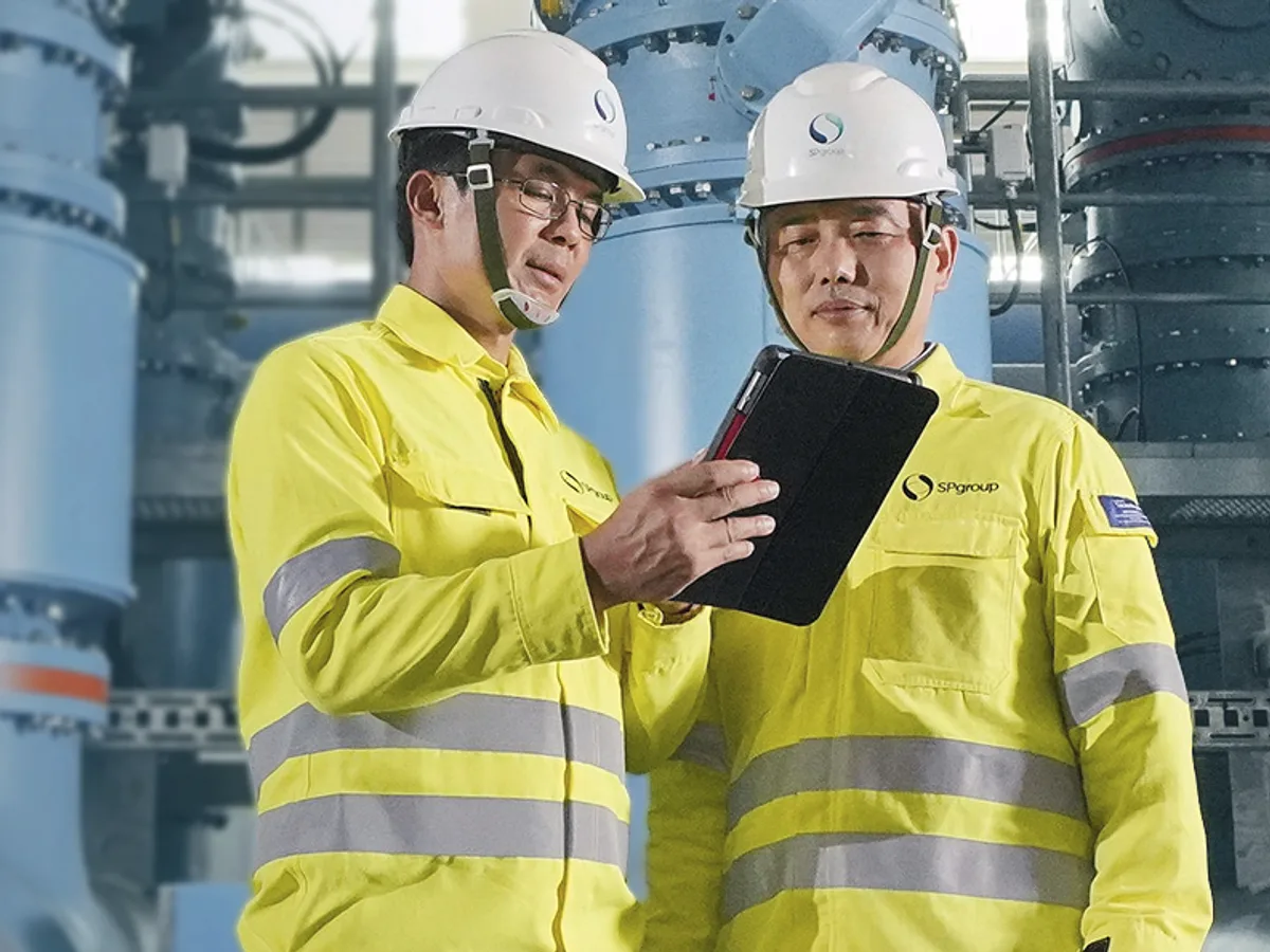 SP engineers reviewing a tablet in front of transformer bays